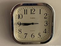 Front view of Cardinal square gold-tone wall clock showing face, numerals, hands, and bezel
