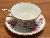 Teacup sitting on saucer showing floral pattern and gold trim