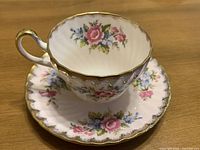 Teacup on saucer, showing interior floral design and gold trim