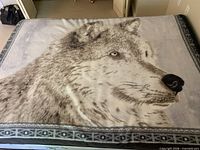 Throw blanket laid flat on bed showing full wolf print design and border