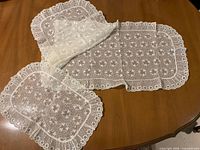 Runner and two placemats laid out showing lace pattern, color and edges