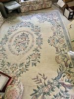 Full view of rectangular rug on floor showing overall floral border and field