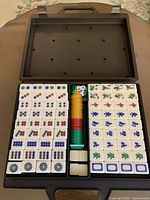 Open case showing organized 144 tiles, chips, dice