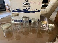 Sample of six jars in various sizes with metal lids in front of box