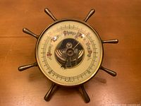 Front view showing brass ship wheel form and dial details
