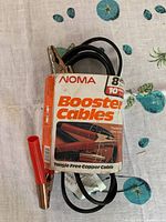 Coiled booster cables in original worn NOMA box showing clamps and cable