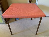 Overall view of the folding card table with orange padded top and metal legs