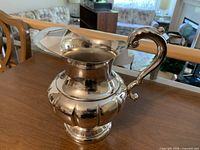 Full view of silver-plated ornate pitcher showing handle, body shape and spout