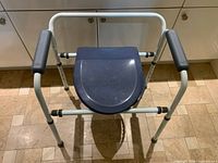 Full view of commode showing frame, seat, armrests and adjustable legs