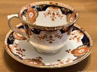 Teacup on saucer, side view showing pattern and gilt trim