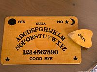 Wooden Ouija board and matching planchette on tabletop