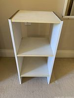 Front view of white three-tier bookshelf showing structure and wear