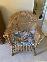 Full view of rattan armchair and floral cushion