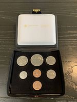 Open presentation case showing all seven coins in velvet insert