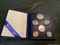 Open presentation folder showing full 7-coin set and RCM ribbon