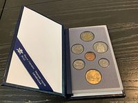 Closed presentation folder opened showing all seven proof coins in insert