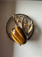 Front view showing tiger eye stone, filigree leaves and circular frame