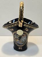 Full view of black porcelain basket vase showing castle scene, gold handle and trim
