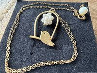 Necklace laid flat showing pendant, chain, and opalescent clasp bead