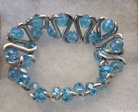 top view of blue/aqua AB faceted glass bead stretch bracelet with silver-tone metal links