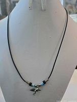 Full view of black cord necklace with surfer pendant and bead arrangement