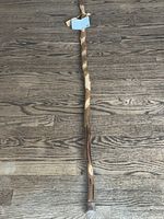 Full view of carved hickory walking stick on wooden floor