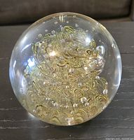 overall view of clear glass sphere showing gold swirls and bubble inclusions
