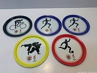 All five metal Coca-Cola Atlanta 1996 Olympic coasters showing rim colors and sport designs