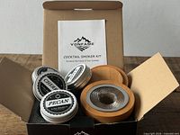 Open box showing smoker lid, four tins of wood chips, instruction booklet