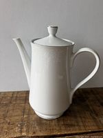 Front view of white fine china coffee pot with lid