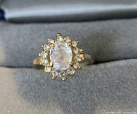 Top view of gold tone halo ring showing oval center stone and halo of accent stones