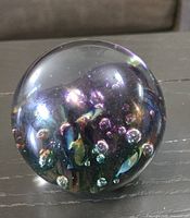 Front view of iridescent glass paperweight showing multicolor finish and internal bubbles