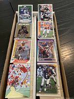 Open two-row storage box showing assorted football cards in sleeves
