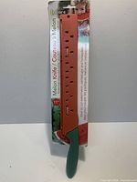 Packaged Luciano melon knife showing orange sheath, green handle and branding