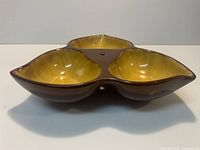 Oblique view of tri-lobed brown and yellow ceramic divided serving dish