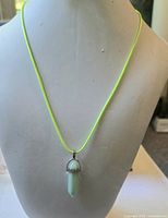 Full view of necklace displayed on bust showing pendant and neon green cord