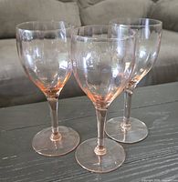 All three pink-stem clear-bowl wine glasses on tabletop