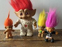 Group shot of four troll dolls on wood surface