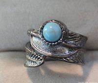 Front view of silver-plated feather motif ring with turquoise cabochon