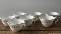 Seven Corelle Butterfly Gold cups lined up