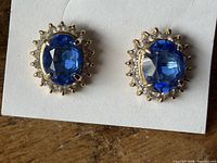 Front view of both earrings showing blue centre stones and clear halo