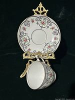 Front view of teacup set on stand showing pattern and gilt details