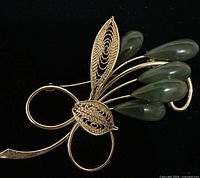 Front view of gold-tone filigree brooch showing six dark green teardrop cabochons and overall design