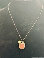 Full view of necklace on display form showing chain and charms