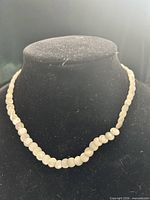 Full view of necklace on display bust showing overall strand and bead arrangement