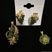 Front view of earrings and two pendants on black background