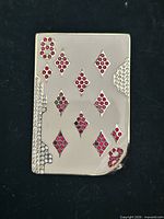 Full view of brooch showing ivory enamel face, red crystal pips, and clear crystal border