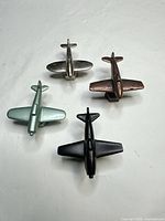 Top view of four airplane-shaped knobs showing finishes and shapes