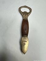Full view of brass and wood bottle opener showing both brass ends and wood handle