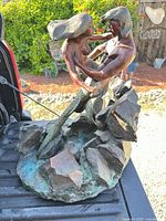 Full view of bronze mermaid and merman sculpture on tailgate